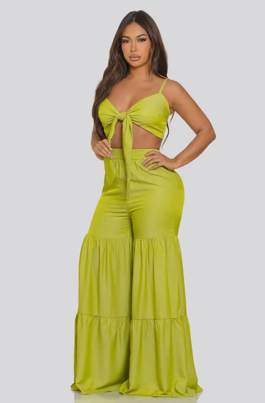 Woman wearing a bright green jumpsuit with cut-out design on a white background